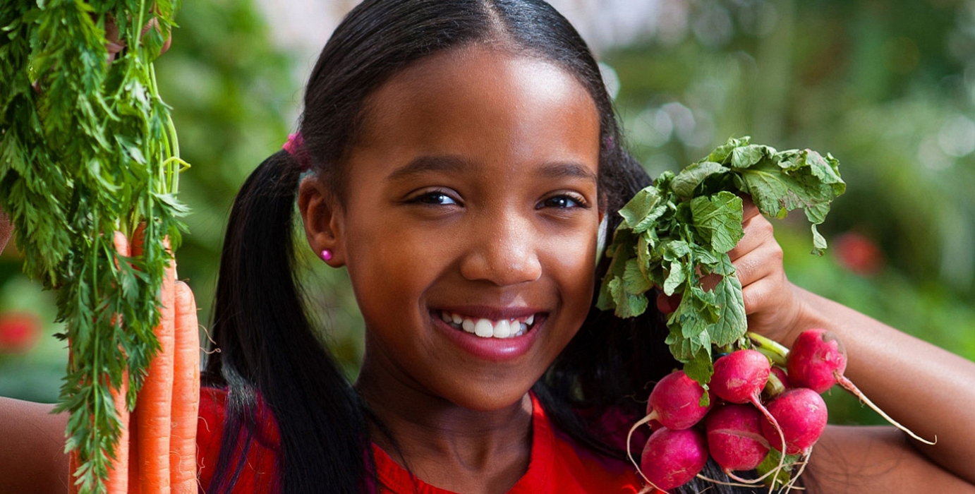 Girl holding radishes and carrots