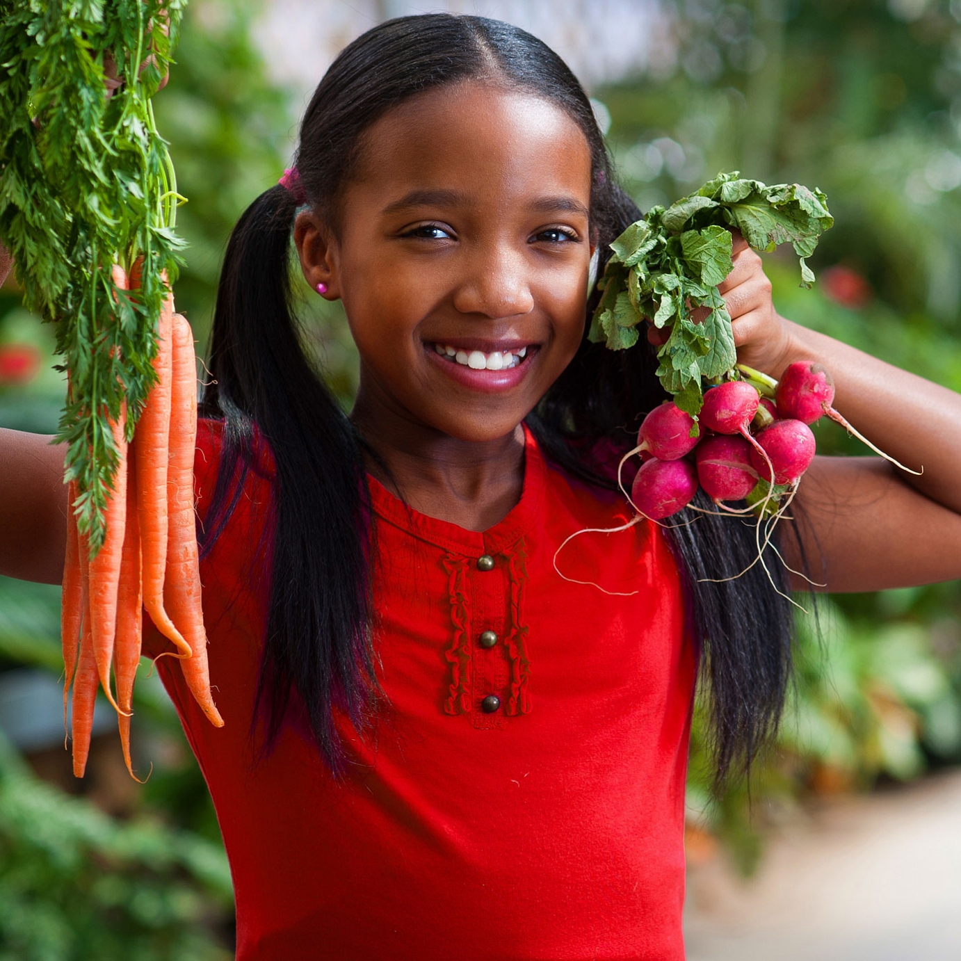 Girl holding carrots and radishes