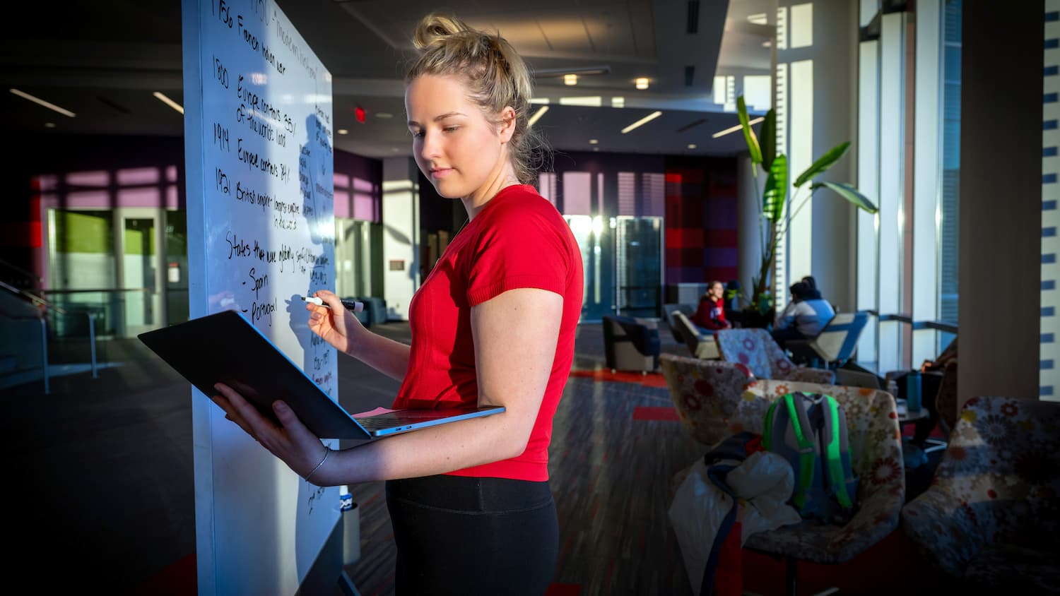 A student writes on a whiteboard in Hunt Library.