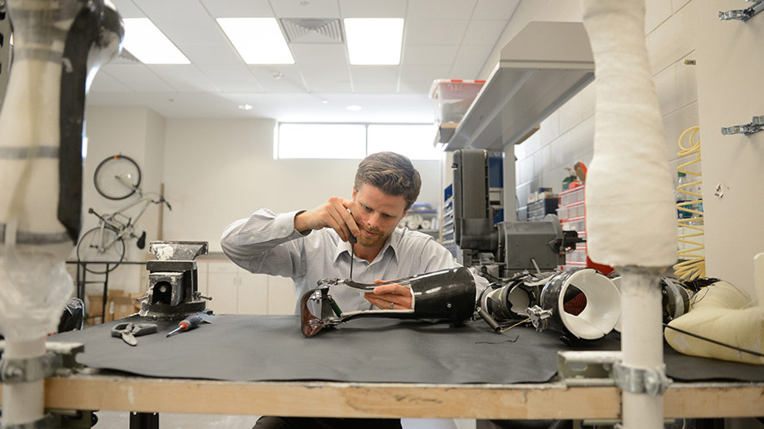 A wide shot of a man working in a lab, showing excess and cluttered space in the background.