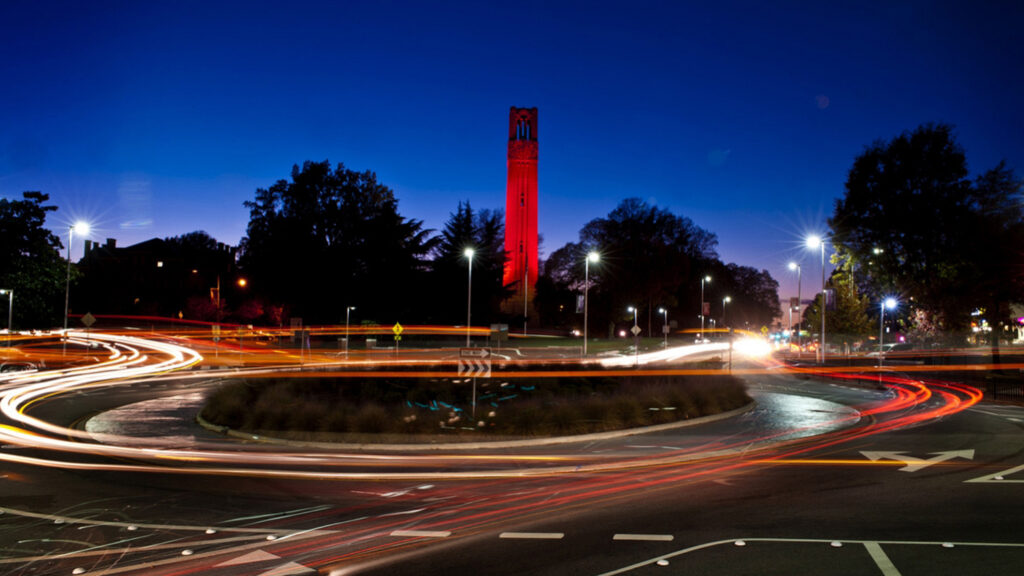 The Belltower lit red, along with a bustling roundabout on Hillsborough Street.